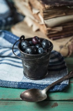 Kırsal ahşap arka planda yaban mersinli küçük bir kova.