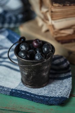 Kırsal ahşap arka planda yaban mersinli küçük bir kova.
