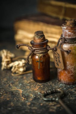 Şişelerde sihirli iksirler, antik kitaplar ve ahşap arka planda büyücülük bitkileri, Cadılar Bayramı teması