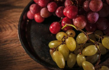 Tahta masada taze kırmızı ve yeşil organik üzümler, seçici bir odak.