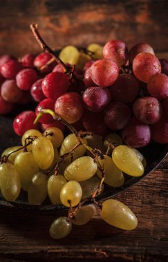 Tahta masada taze kırmızı ve yeşil organik üzümler, seçici bir odak.
