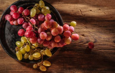 Tahta masada taze kırmızı ve yeşil organik üzümler, seçici bir odak.