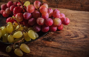 Tahta masada taze kırmızı ve yeşil organik üzümler, seçici bir odak.