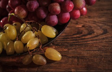 Tahta masada taze kırmızı ve yeşil organik üzümler, seçici bir odak.