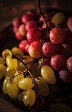 Tahta masada taze kırmızı ve yeşil organik üzümler, seçici bir odak.