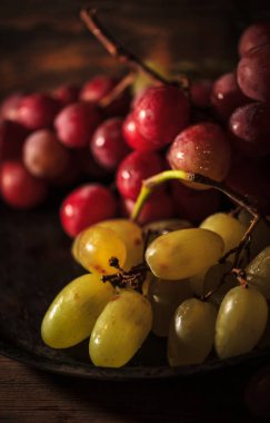 Tahta masada taze kırmızı ve yeşil organik üzümler, seçici bir odak.