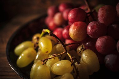 Tahta masada taze kırmızı ve yeşil organik üzümler, seçici bir odak.
