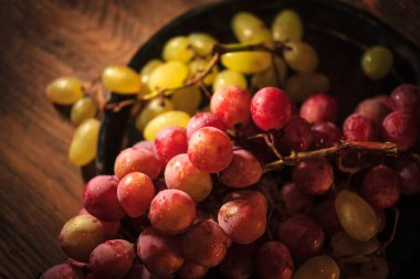 Tahta masada taze kırmızı ve yeşil organik üzümler, seçici bir odak.