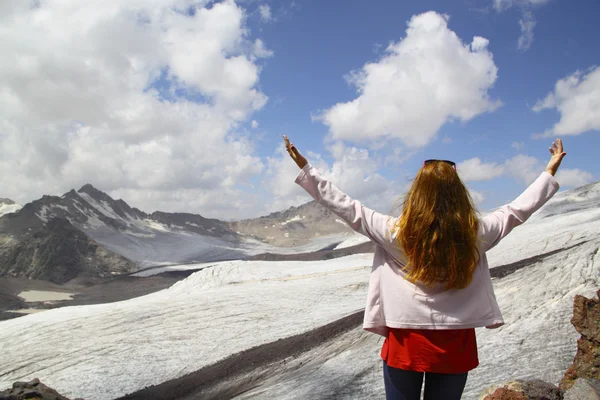 Een jong meisje staat op de rand van een klif en kijken naar de sk — Stockfoto