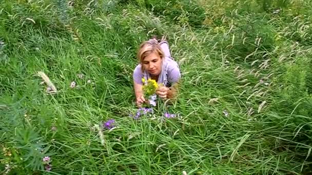 Gelukkige vrouw liggen op groen gras in de weide — Stockvideo