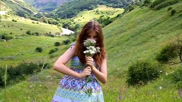 Jovem feliz com um buquê de margaridas em um prado nas montanhas — Vídeo de Stock