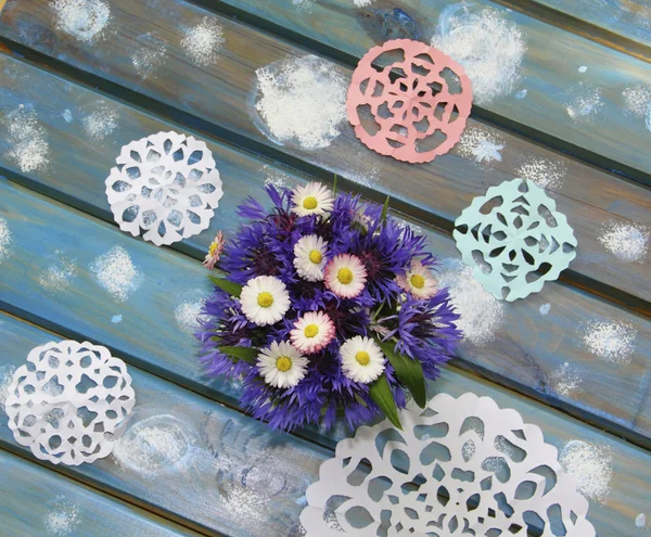 Lovely paper snowflakes and a bouquet of flowers on a blue woode — Stock Photo, Image