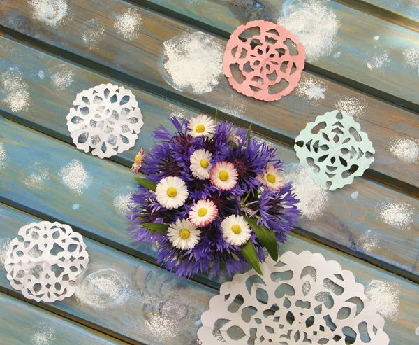 Lovely paper snowflakes and a bouquet of flowers on a blue woode Stock Image