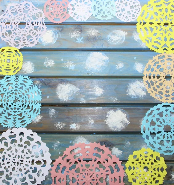 Geschnitzte bunte Papierschneeflocken auf blauem Holzgrund, — Stockfoto