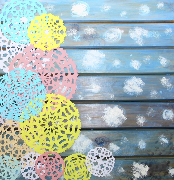 Copos de nieve de papel colorido tallado sobre un fondo de madera azul, Ch —  Fotos de Stock