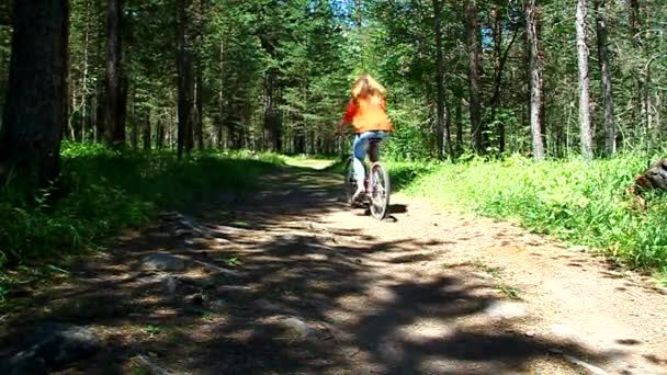 Young girl riding a bike in the forest on a dirt road — Stock Video