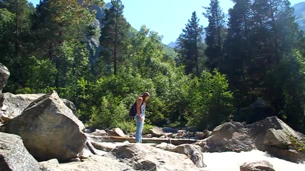 Una giovane turista che cerca di attraversare il fiume turbolento — Video Stock