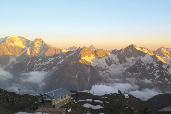 Egy kis szálloda a hegyeket világítja meg a lenyugvó nap — Stock Fotó