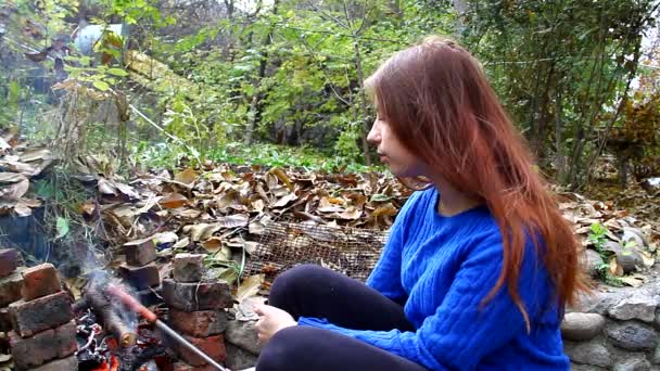 Jovem menina fritar salsicha em um fogo ao ar livre e comê-lo — Vídeo de Stock