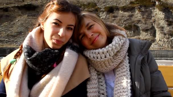 Mor och dotter sitter på en parkbänk tillsammans, kramar, kyssar och skrattar — Stockvideo