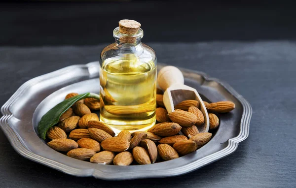 Almond oil in transparent bottle with almonds
