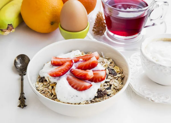 Tigela de café da manhã com muesli, iogurte e morangos, chá e frutas — Fotografia de Stock