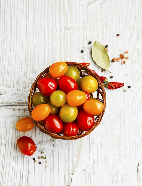 Cherry rajčata sortimentu v koši s kořením — Stock fotografie