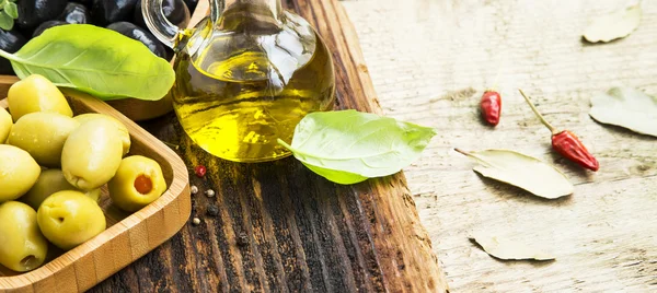 Azeitonas verdes e pretas orgânicas com azeite e manjericão sobre madeira — Fotografia de Stock