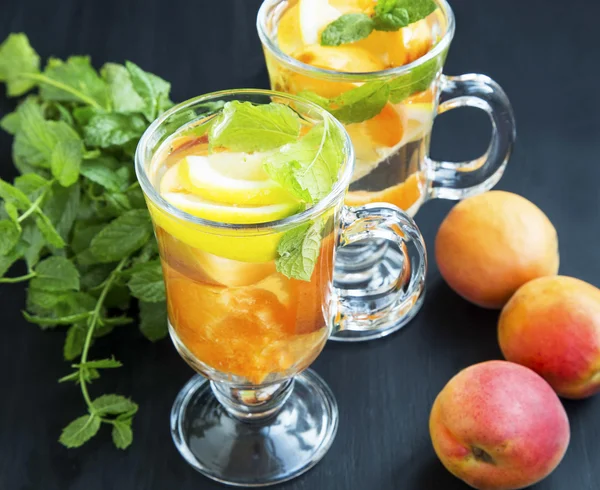 Agua de frutas con albaricoques, limones y hierbabuena en vasos — Foto de Stock
