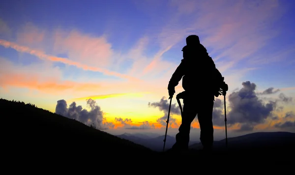 Silueta de excursionista en pico de montaña mirando al atardecer — Foto de Stock