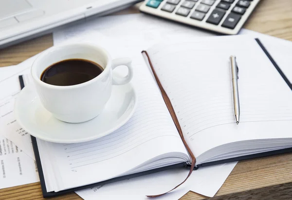 Taza de café en la oficina con documentos financieros, agenda y calculadora — Foto de Stock