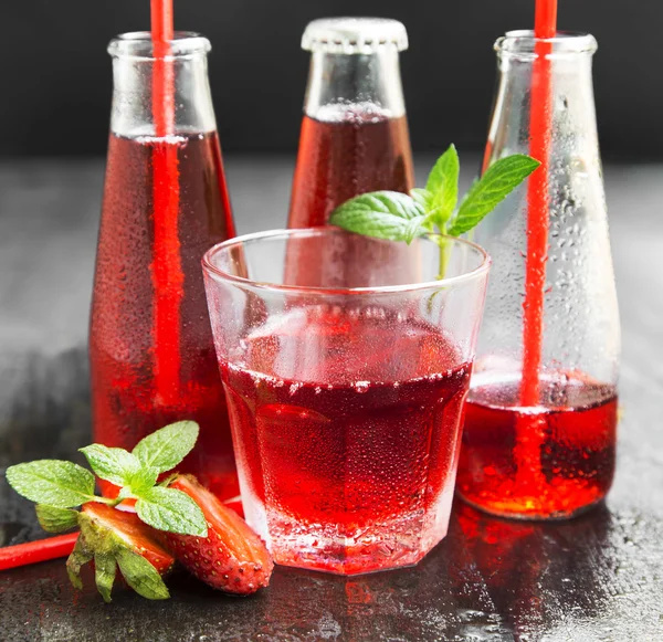 Erfrischender roter Saft in transparentem Glas und Flaschen mit Stroh — Stockfoto