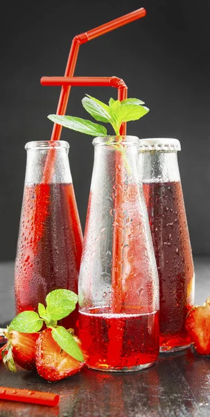 Erfrischender roter Saft in transparenten Flaschen mit Erdbeere, min — Stockfoto