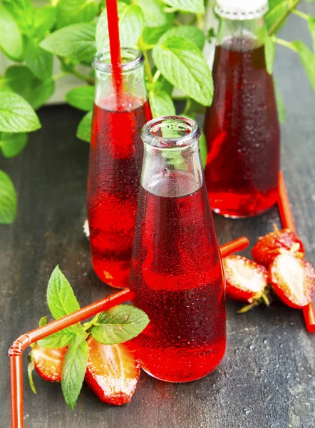 Erfrischender roter Saft in transparenten Flaschen mit Erdbeere, min — Stockfoto