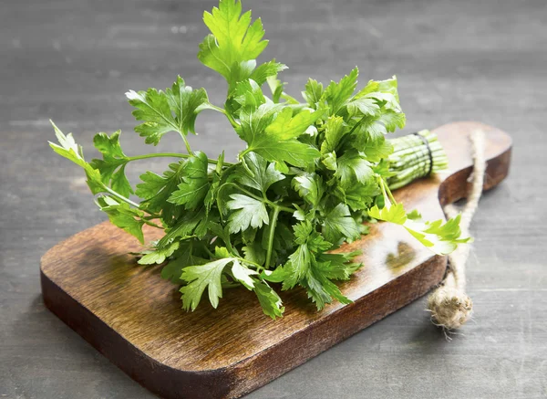 Hierba culinaria de perejil en un tablero de madera de corte — Foto de Stock