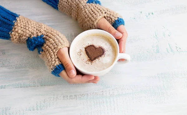 Segurando café Latte com acolhedores aquecedores de mão de lã — Fotografia de Stock