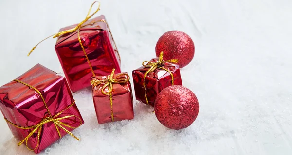 Rote Weihnachtsgeschenke und Glitzerkugeln im Schnee — Stockfoto