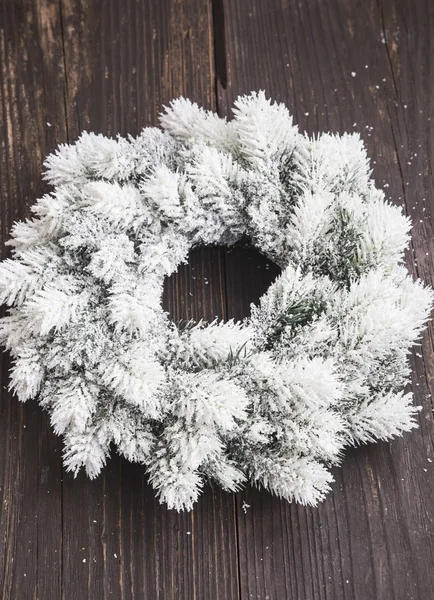 Corona de Navidad nevada sobre fondo de madera — Foto de Stock