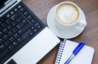 Laptop, kahve fincanı ve bir defter ile Office nesneleri