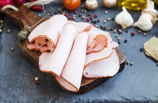 Prosciutto di maiale fette e pepe macinato su tagliere di legno — Foto Stock