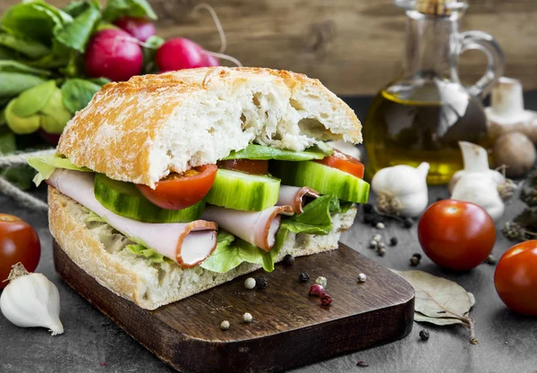 Sandwich con jamón, tomates, ensalada, pan fresco y pepinos en un — Foto de Stock