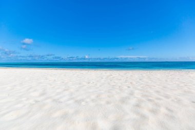 Güzel bir plaj geçmişi. Yumuşak kum, mavi deniz, mavi gökyüzü ve tüylü bulutlarla tropik sahil manzarası. Tropik sahil manzarası. Sakin ve rahatlatıcı boş plaj sahnesi, mavi gökyüzü ve beyaz kum. Sakin doğa kavramı