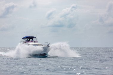 Hızlı motorlu tekne, bulutlu gökyüzü ile tropikal denizde dalgalanan dalgalara yaklaşıyor.. 