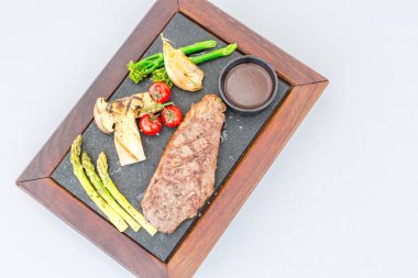 Siyah taşın üstünde taze biftek. Baharatlı ve ızgara sebzeli orta pişmiş biftek.