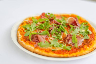 Yakın plan pizza, ahşap pizza tahtasında taze roka ile süslenmiş. Parlak taş arkaplanı