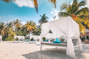 Egzotik plaj sahnesindeki gölgelik. Beyaz kumsal gölgeleri. Tropikal bir tatil köyünde lüks plaj çadırları. VIP plaj deniz manzarasında konforlu bir kanopi. Yaz tatili tatil beldesi konsepti için turizm tasarımı.