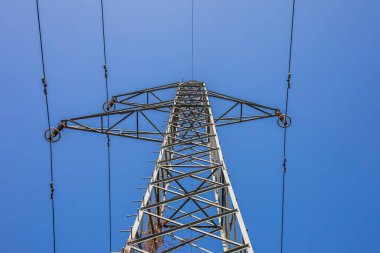 Mavi gökyüzünün altında yüksek voltaj direği. Yüksek voltajlı gökyüzü arka planı. Gün batımında elektrik iletim güç hatları (yüksek voltaj kulesi)