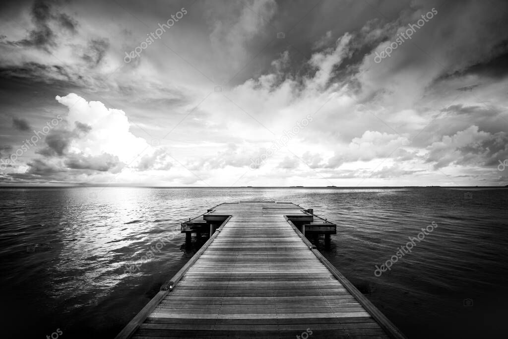 Dramatic sunset dramatic sky over wooden boards pier, calm sea  relaxing ocean horizon. Beach pier and dramatic seascape view