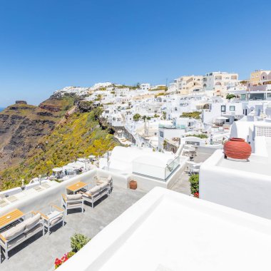 Oia ve Fira şehirleri, Yunanistan 'ın Santorini adası: Panoramik manzara, Caldera, Ege denizi üzerinde mavi kubbeleri olan geleneksel beyaz mimari ve ünlü beyaz evler ve kiliseler üzerinde güneşli gökyüzü. Lüks yaz tatili, romantik tatil.
