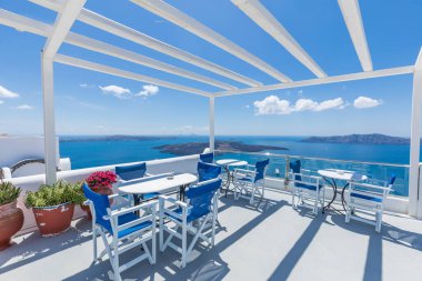 Açık çatı restoranının deniz manzaralı güzel terası. Santorini Adası, Yunanistan. Rahatlatıcı yaz tatili ve tatil konsepti. Caldera 'daki sandalyeler ve masalar, 